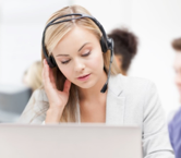 Eine junge Teilnehmerin mit Headset sitzt vor ihrm aufgeklappten Laptop und verfolgt aufmerksam das Webinar der g.a.s.t.-Akademie.