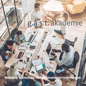 g.a.s.t.-Akademie | iStock Das Imagebild der g.a.s.t.-Akademie zeigt eine Gruppe junger Menschen mit Laptops an einem Tisch zusammenarbeiten.